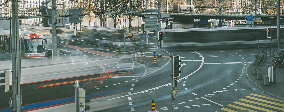 Verschiedene Busse der VBL AG an der Kreuzung vor dem Bahnhof Luzern bei herbstlichem, sonnigem Wetter.